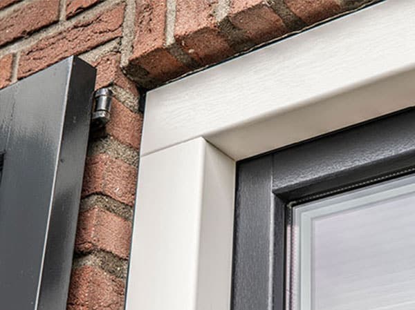 Buitenunit van een warmtepomp tegen de gevel van een woning.
