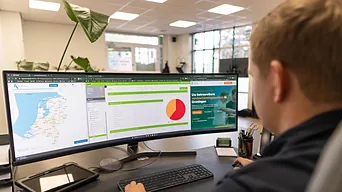Een adviseur van Gemakkelijk Verduurzamen werkt op kantoor aan een energielabel op een breed scherm.