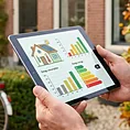 Een adviseur houdt een tablet vast voor een woning tijdens de opname.